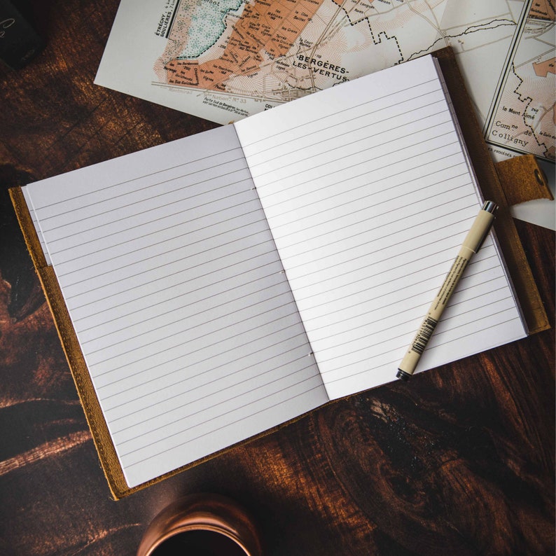 Open leather journal showing lined pages with pen