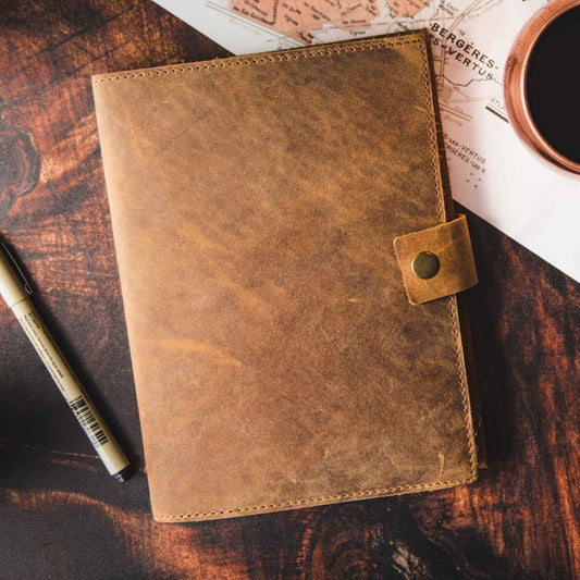 Brown leather journal with flap closure and brass button