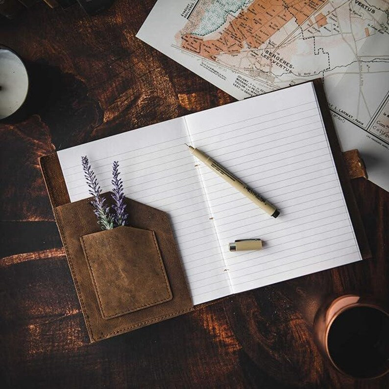 Person writing in leather journal outdoors